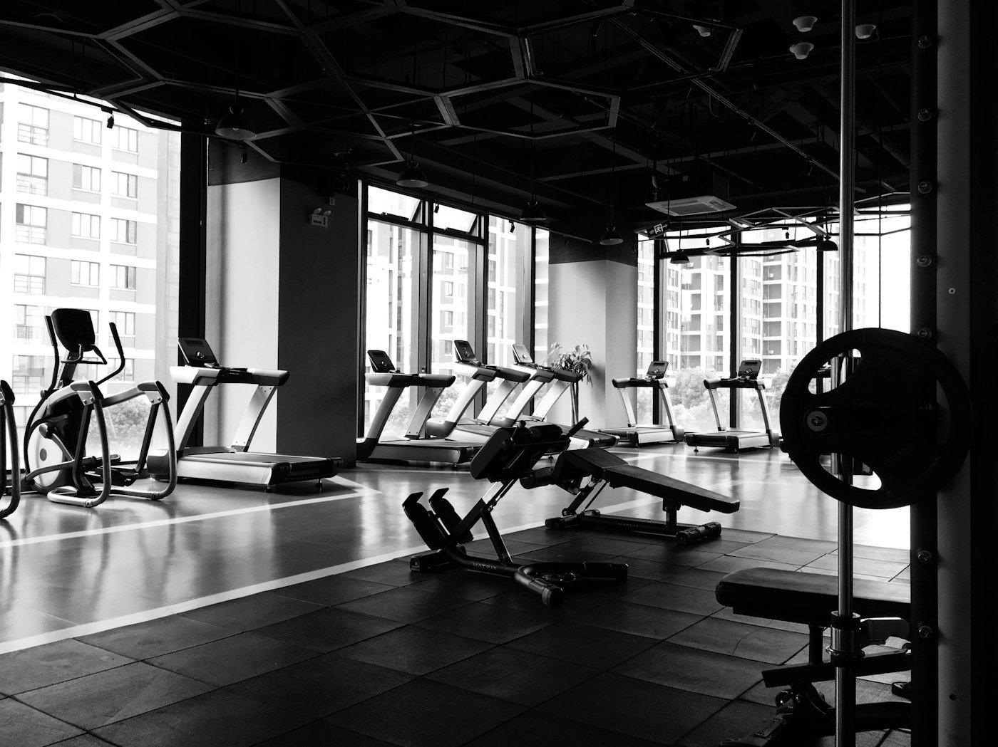 A quiet gym floor with benches, racks and conditioning equipment.