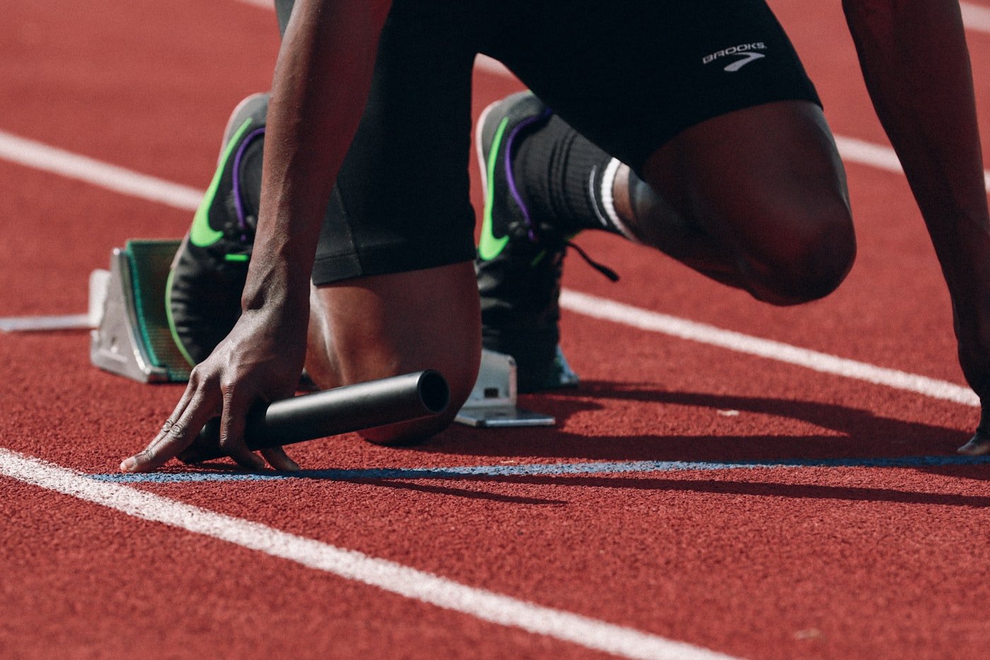 A sprinter crouched in the blocks at the start line of a track.